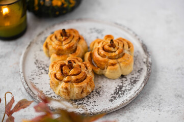 Pumpkin cinnamon rolls. Fresh homemade Cinnamon Rolls in the form of pumpkins. Bakery for Halloween or Thanksgiving party. Cozy autumn, winter still life with pumpkins.