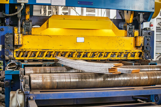 Industrial metal guillotine machine in operation at a workshop, cutting metal sheets with precision and efficiency