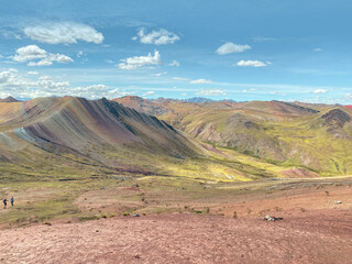 Breathtaking panoramic view of Palccoyo Rainbow Mountain in Peru, less touristy than Vinicunca, but more accessible from Cusco for travellers and tourists. Bright sunny day, tiny people in landscape.