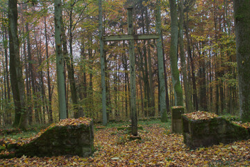 Ancient medieval graveyard with holy cross in autumn forest Halloween