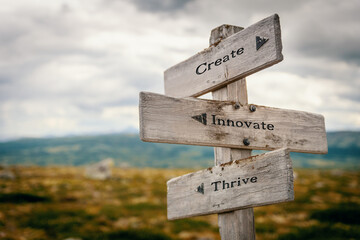 create innovate thrive text quote written on wooden signpost at the crossroads outdoors in nature.