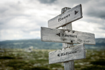 reset restart refocus text quote written on wooden signpost at the crossroads outdoors in nature.