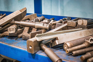 A cluttered workbench filled with various tools for metalworking in a workshop setting during the...