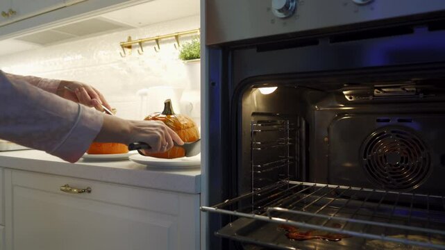 Woman preparing stuffed red kuri squash in the kitchen. Stuffed orange colored winter squash baked in the oven ready to eat.