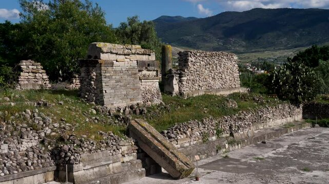 Slow motion landscape of historic rocky stone wall ruins in Mitla archaeology site courtyard castle landmark Tlacolula Valley Oaxaca city village Mexico culture travel tourism