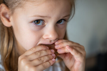 Little girl eating Dubai chocolate with pistachio paste and kataifi dough. Confectionery handmade sweets at home in the kitchen. 