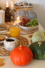 Pumpkins, various food and drinks, fall decorations, books and candles on the table. Fall hygge at home. Selective focus.
