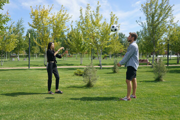 A couple is actively engaged in a game of volleyball, laughing and enjoying their time together in...