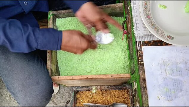 The process of molding traditional Indonesian cakes. This cake is made from sticky rice filled with liquid brown sugar, then steamed using a bamboo mold called putu.