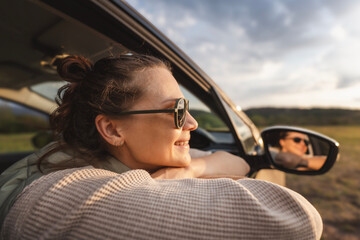 Happy young woman passenger looking out of car window, auto travel and adventure