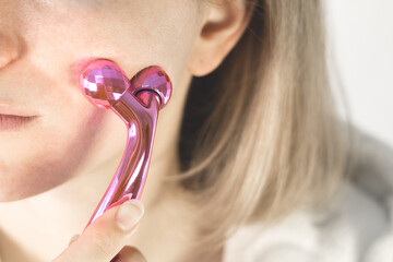 Woman is massaging her face. Face massager for skin care, reduce puffiness and improve wrinkles.