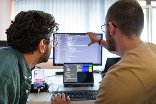 Programmers engrossed in deep collaboration, diligently working together to solve complex problems and develop innovative mobile applications with seamless functionality.