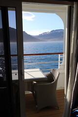 peaceful setting of an empty private balcony on a cruise ship sailing through an Icelandic fjord in...