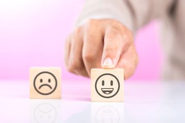 A man choosing between a happy and sad face on wooden blocks, ultimately selecting the happy one. The concept of starting each day with positivity, emphasizing the importance of a bright outlook