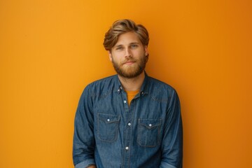 Fototapeta premium A man with a beard stands in front of an orange wall, great for use in editorial or commercial contexts