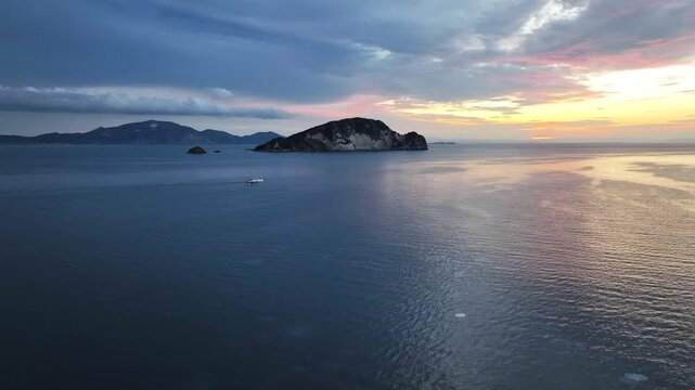 sailboat on the ionian sea in Zakynthos greece at sunrise with large Rhizostoma pulmo jellyfish floating in the water and island marathonisi in the background AERIAL ORBIT