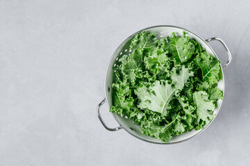 Curly Kale. Fresh raw chopped Curly Kale in colander on gray stone background, top view. Ready for delicious healthy salad, vegan food, superfood.