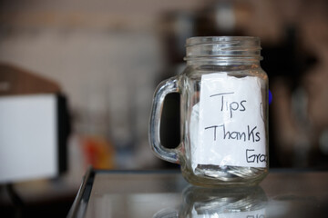 Tip jar on the counter filled with bills
