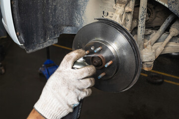 Auto mechanic cleaning a new brake disc from factory oil with a spray can, close-up