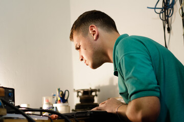  repairman working meticulously on a laptop, using a soldering tool to fix electronic components....