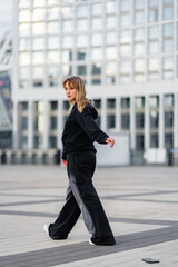 Young woman in black athletic wear walking outdoors in urban setting