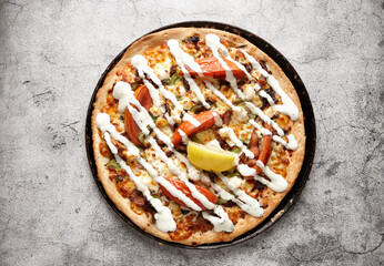 Vegetarian supreme pizza drizzled with white sauce and topped with a lemon slice