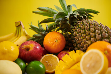 Vibrant assortment of fruits including pineapple, oranges, lemons, bananas, and apples arranged in colorful display showcasing natural beauty of produce