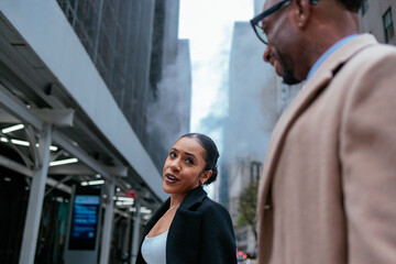 Fototapeta premium Businesswoman and businessman having a conversation walking on city street