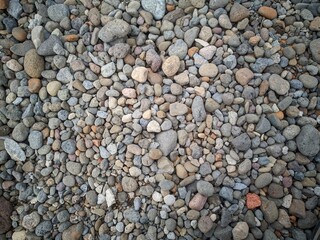 Background of smooth round pebble texture. Cover pebbles of various colors and patterns, gray pebbles, beige pebbles, reddish pebbles.  Gravel texture.