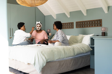 African american female friends enjoying face masks and conversation during cozy spa day at home