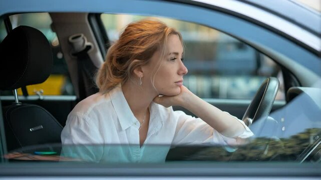 A thoughtful woman gazes out of a car window, lost in contemplation.