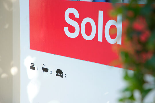 real estate sign with the word “Sold” in white letters