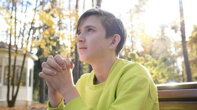 a boy is praying in  an autumn park	