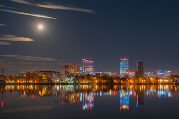 Amazing urban landscape with tall buildings illuminated at night and reflected in the water....