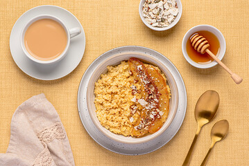 Food photography of millet porridge with caramelized banana, pecan, nuts, coconut flakes, chia, flaxseeds, honey, tea with almond milk