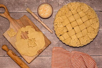 Food photography of raw american apple pie, raw dough, wooden board, rolling pin, egg, brush, wheat flour, preparing food