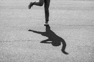 A person playfully balancing on one foot, casting a unique shadow outdoors