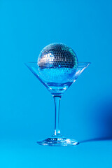 Fototapeta premium Cocktail party with disco ball on sky blue background. Disco party, retro fashion. Modern stylish vertical template for holiday card, banner, flyer, menu with space for text