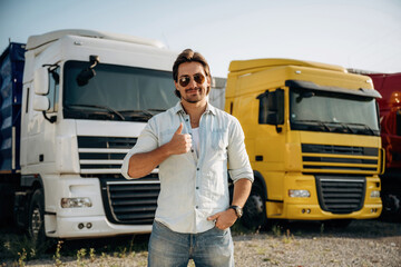 Thumb up, standing. Truck driver is near the transport outdoors