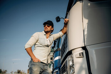 Front view, leaning on the cabin. Truck driver is near the transport outdoors