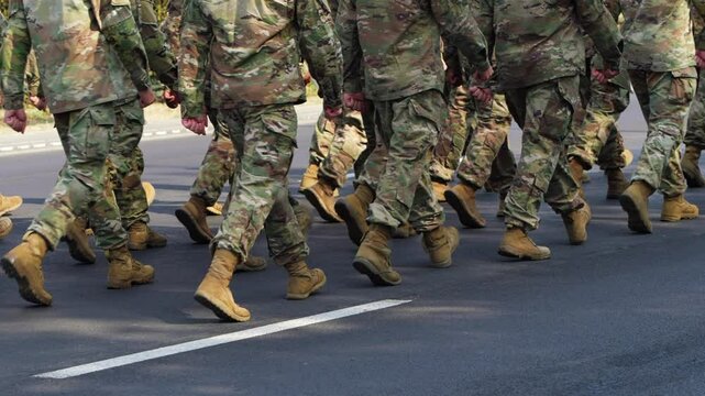 Low angle view field soldiers wearing camouflage and carrying rifles marching together on a sunny day synchronized. Military parade