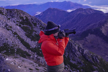 山頂で朝日を撮影する男性登山者