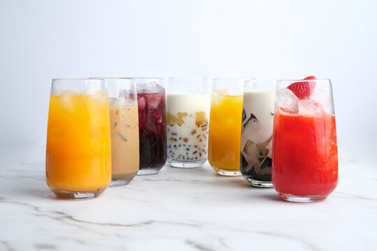 Different kinds of colorful juices in a tall glass served on a white marble countertop