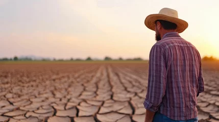 Foto op Canvas Farmer standing in a parched cracked field surveying the desolation caused by rising temperatures and drought conditions © Intelligent Horizons