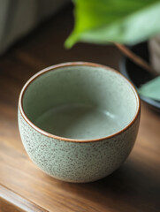 Close-up of a speckled green ceramic bowl on a wooden surface.