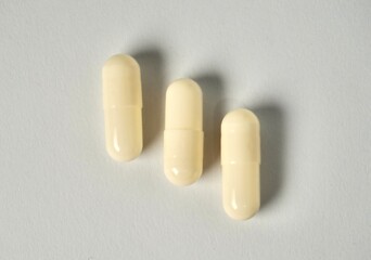 Three white capsule healthcare medicine or vitamin isolated on horizontal ratio plain white background.