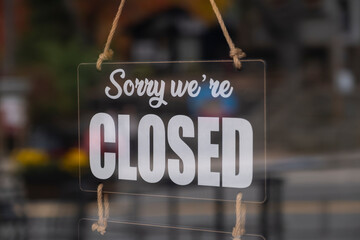 Sign sorry we are closed hanging at the store front glass door.	