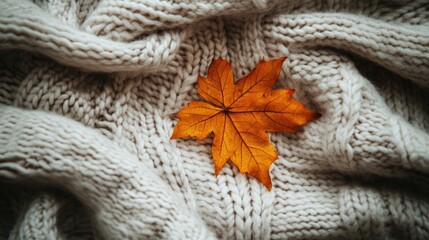 Cozy arrangement featuring an autumn leaf on a merino wool blanket creating a warm and inviting ambiance Flat lay with a knit texture and ample space for text Autumn theme