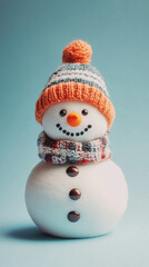 A snowman with a knit hat and scarf is smiling. The hat is orange and the scarf is red and blue