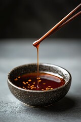 Chopsticks Drizzling Soy Sauce into Bowl